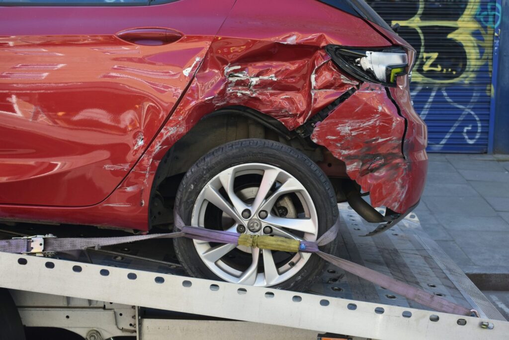 Damaged red car loaded onto a tow truck