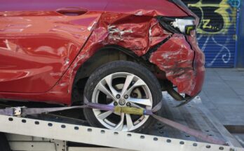 Damaged red car loaded onto a tow truck