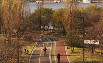 People cycling and walking on a park path near river