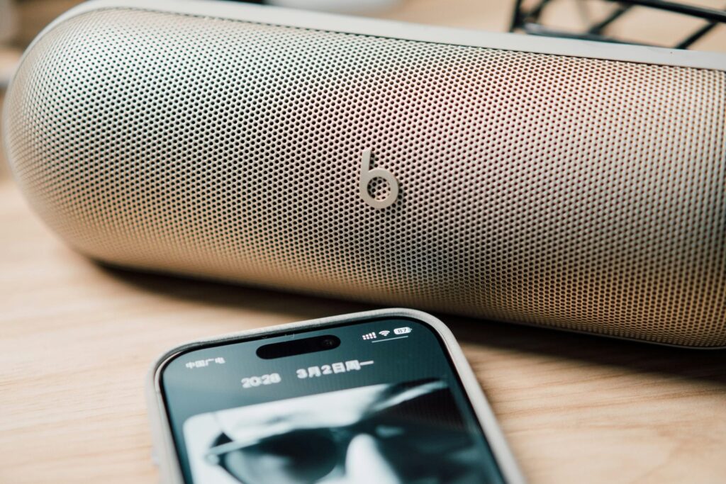 A portable speaker and smartphone on a wooden surface