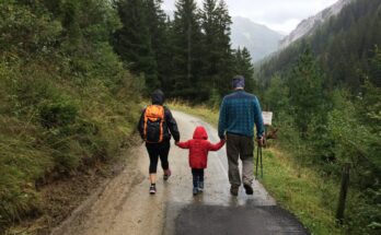 man, woman, and child walking together along dirt road