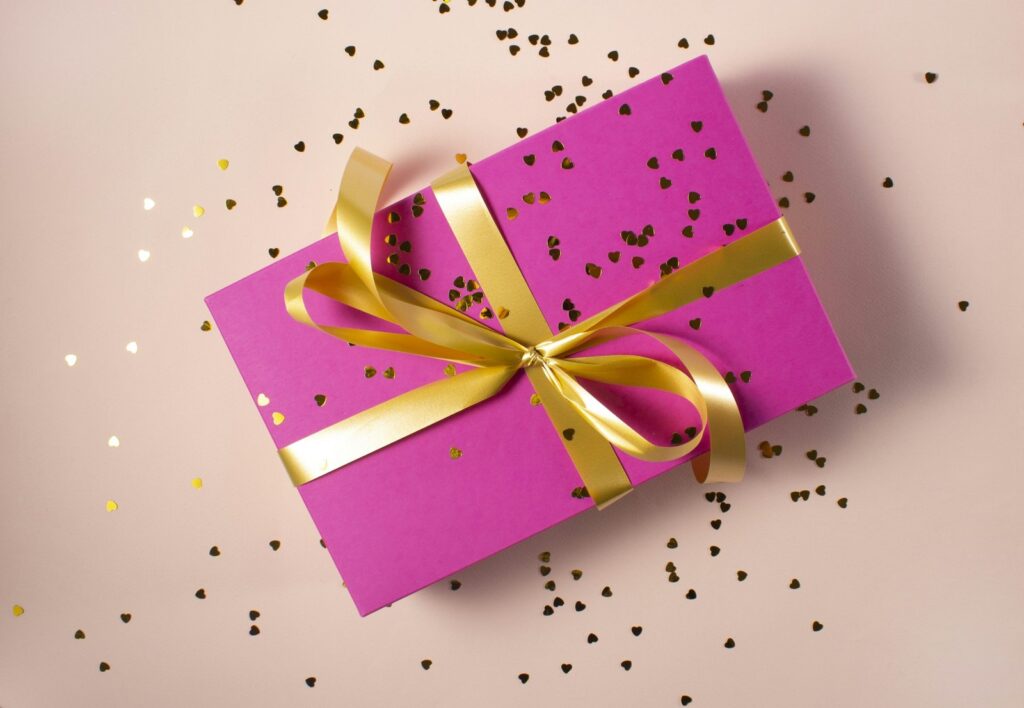 Pink wrapped gift with ribbon and confetti