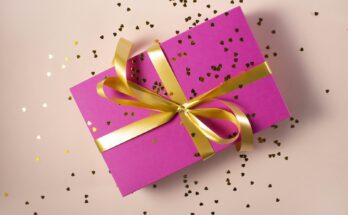 Pink wrapped gift with ribbon and confetti