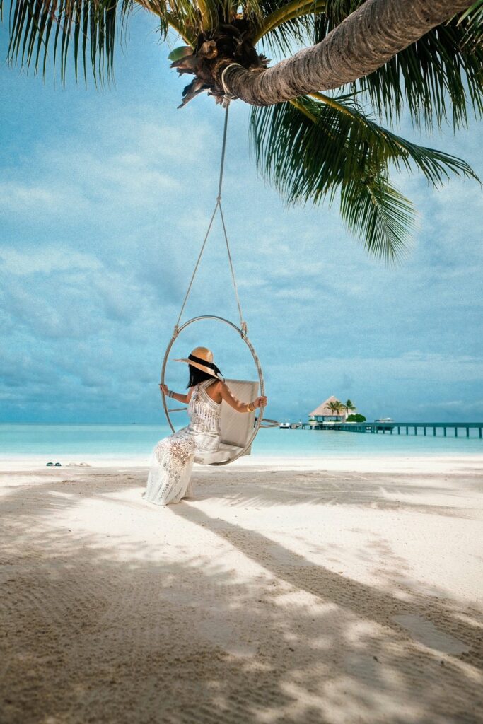 Traveler sitting on a swing above a tropical beach