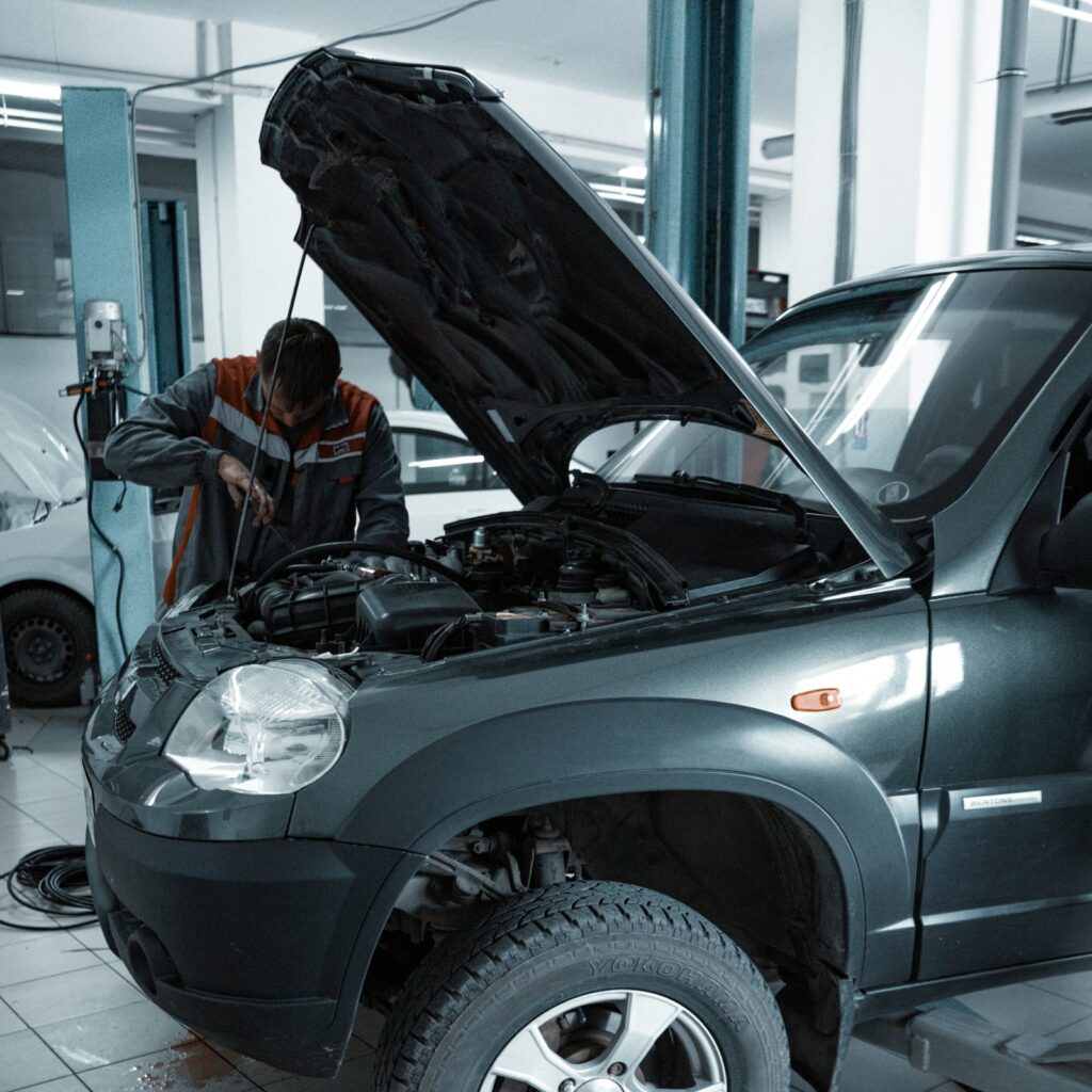 Mechanic examining a car with the hood open