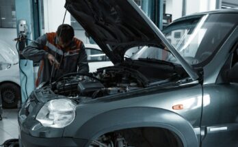 Mechanic examining a car with the hood open