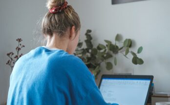 Woman working at a laptop beside a window