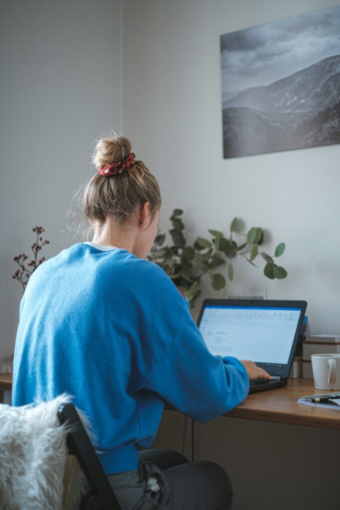 Woman working at a laptop beside a window